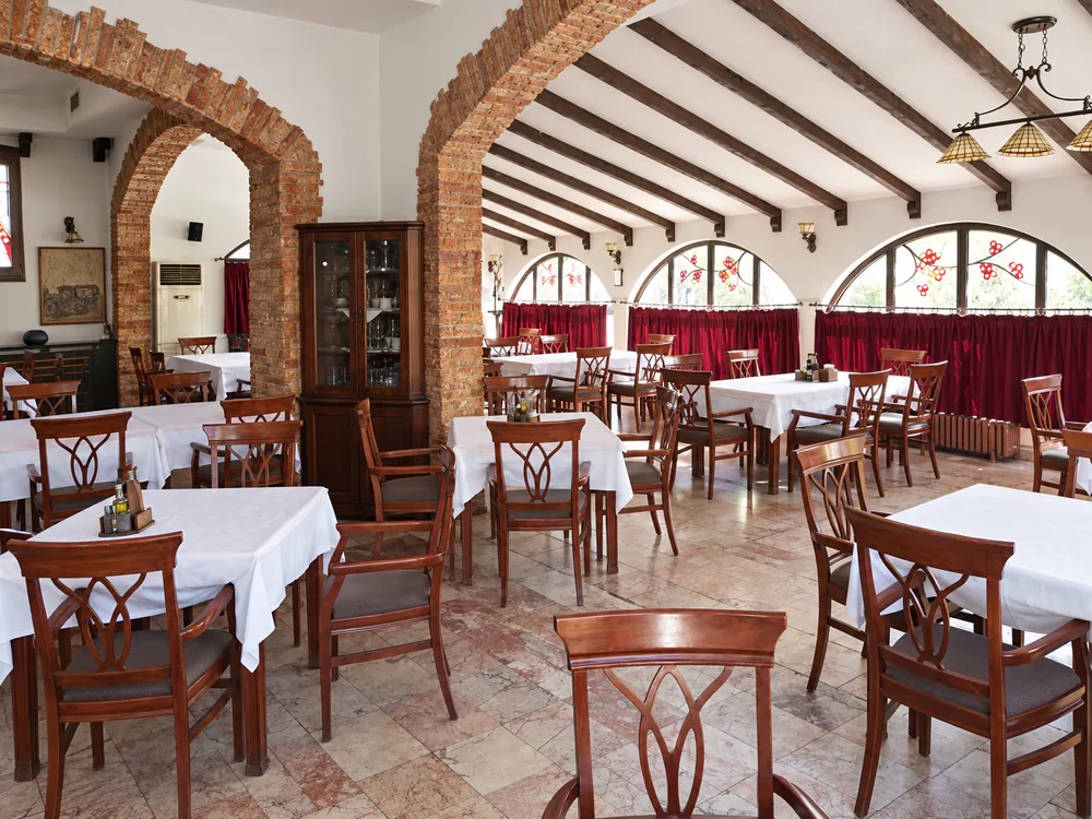 Restaurant Mal Odmor: exposed brick arches, dark timber ceiling beams, white tablecloths and arched stained-glass windows